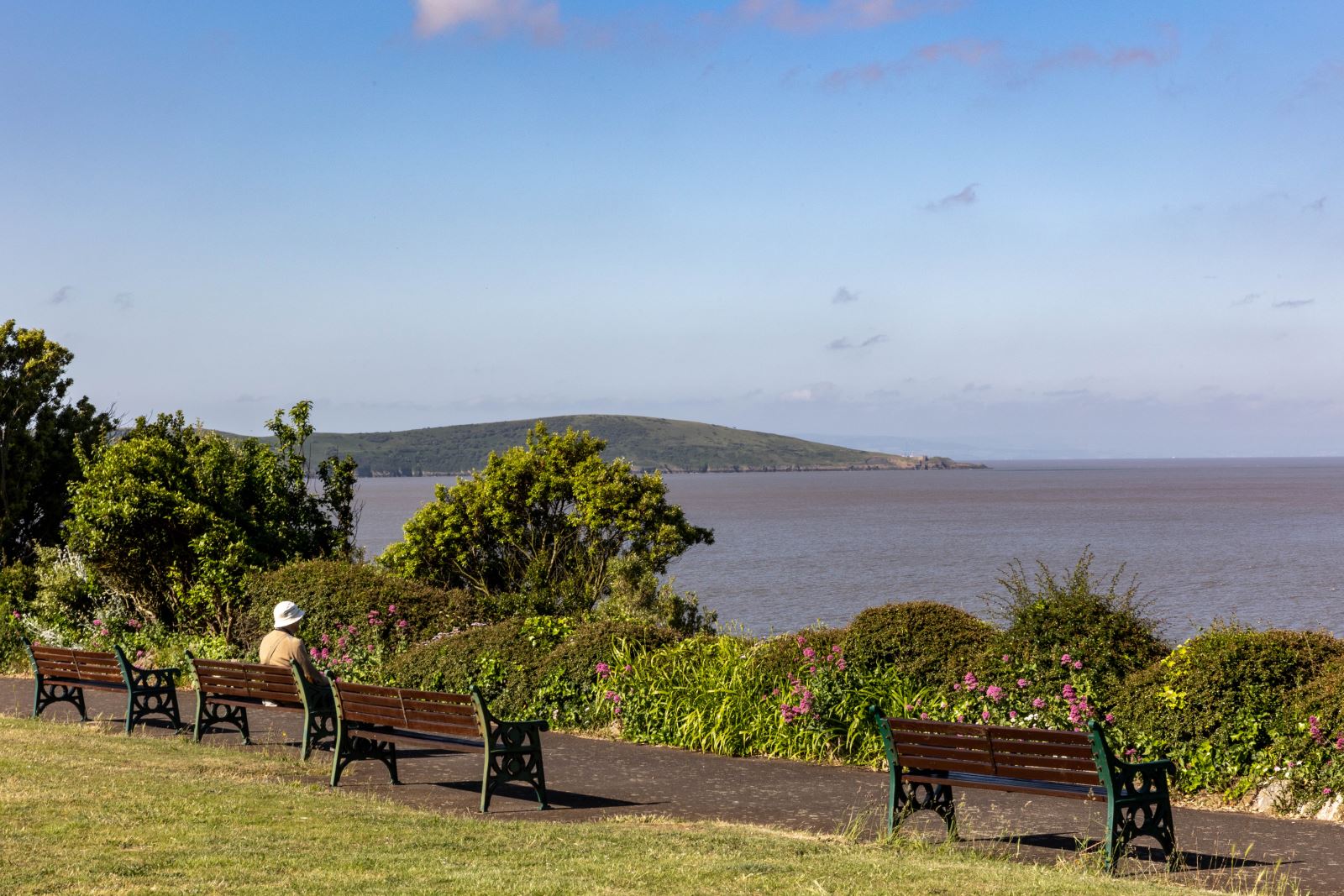 A man sitting on a bench in the Prince Consort Gardens, Weston-super-Mare admiring the view out to sea admiring the 